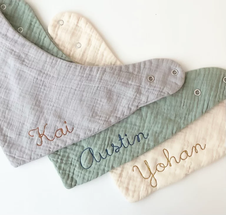 Three baby bibs are displayed on a white surface, showcasing the charm of personalized baby gifts.